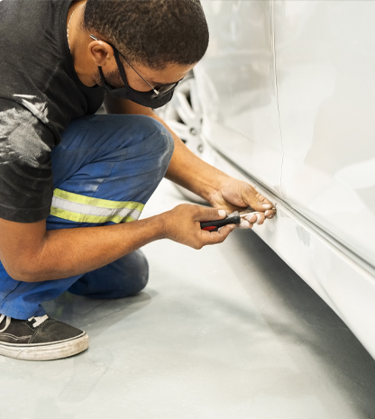 Technician repairing dent in car