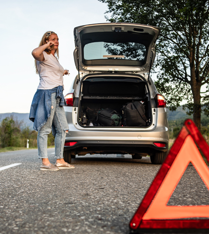 Woman on phone next to broken down car