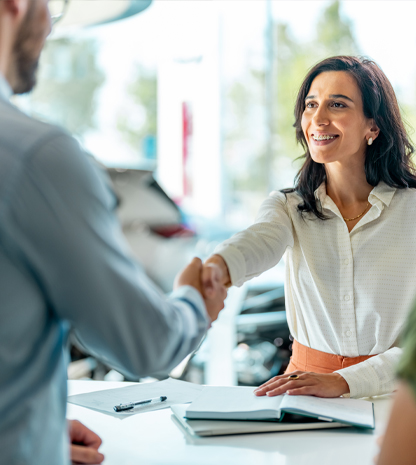 Man and woman shaking hands inside dealership