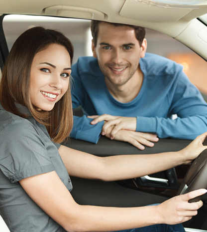 Image of a woman sitting in a car with man peering into drivers window